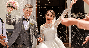 wedding guests smile and clap while looking at the married couple