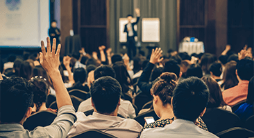 a woman raises her hand during a corporate seminar